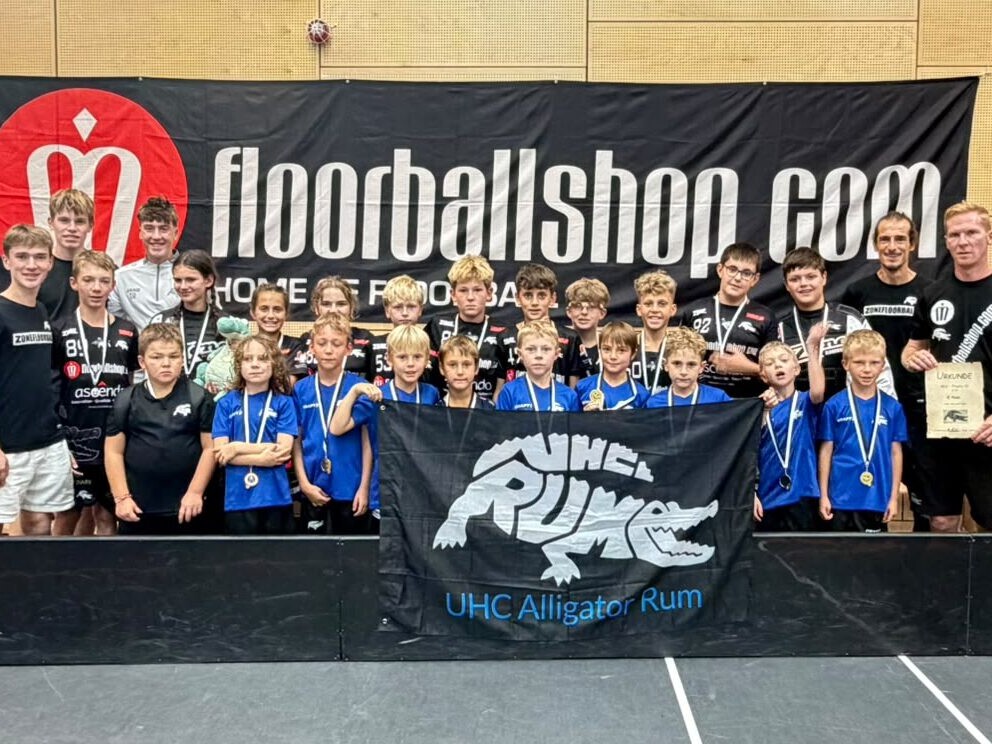 Mannschaftsfoto: Floorballspieler mit Trainerteam in einer Sporthalle